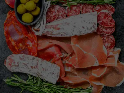 Tabla de embutidos: salami, coppa, jamón curado y fuet, con aceitunas y romero