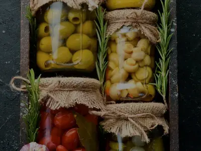 Tarros de aceitunas, champiñones y tomate en conserva dentro de una caja de madera