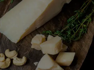Cuña de queso curado sobre tabla de madera, con tomillo fresco y trozos partidos